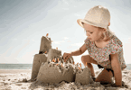 En flicka på stranden som bygger ett standslott av cigarettfimpar.