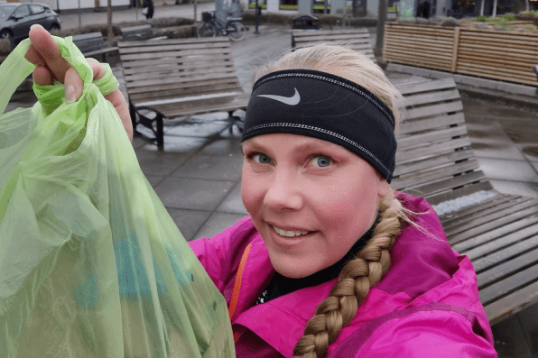 Bild på Malin Taggu i rosa jacka. Hon håller upp en grön påse med skräp.