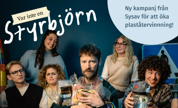 Styrbjörn sitter omringad av flera glada männsiskor medan han håller hårt i sina plastförpackningar.