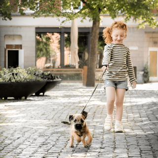 En flicka som går på promenad med en hund.