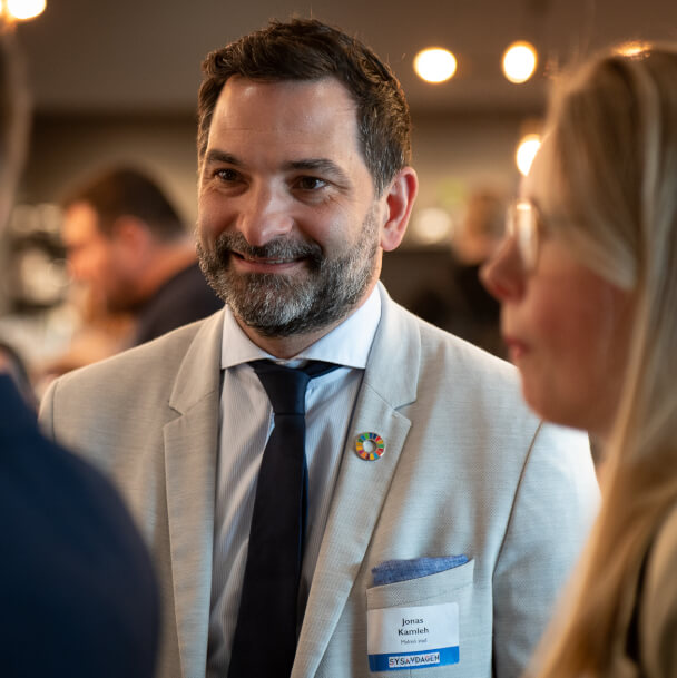 Man som håller en konversation med människor i bakgrunden.