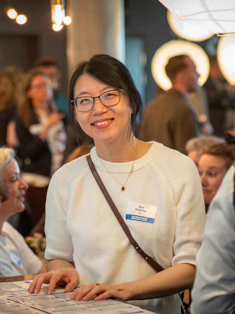 Kvinna som ler med människor i bakgrunden.