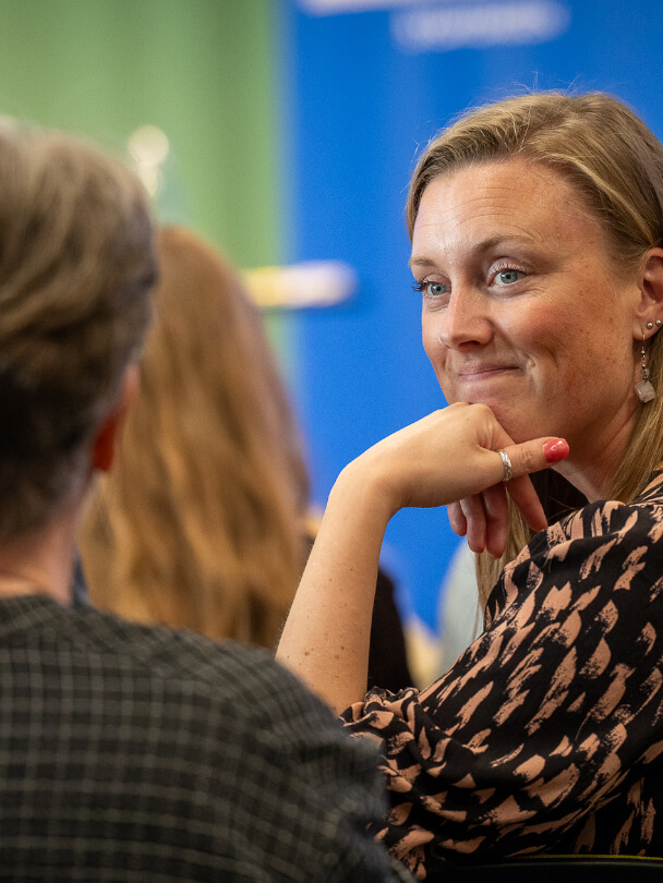 Kvinna som ler och lyssnar på en konversation.